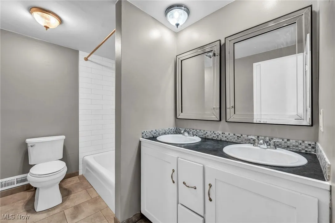 Full bathroom with double vanity, shower / bathtub combination, and light tile patterned floors