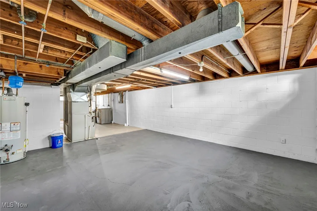 Unfinished basement with water heater, heating unit, and washer / clothes dryer