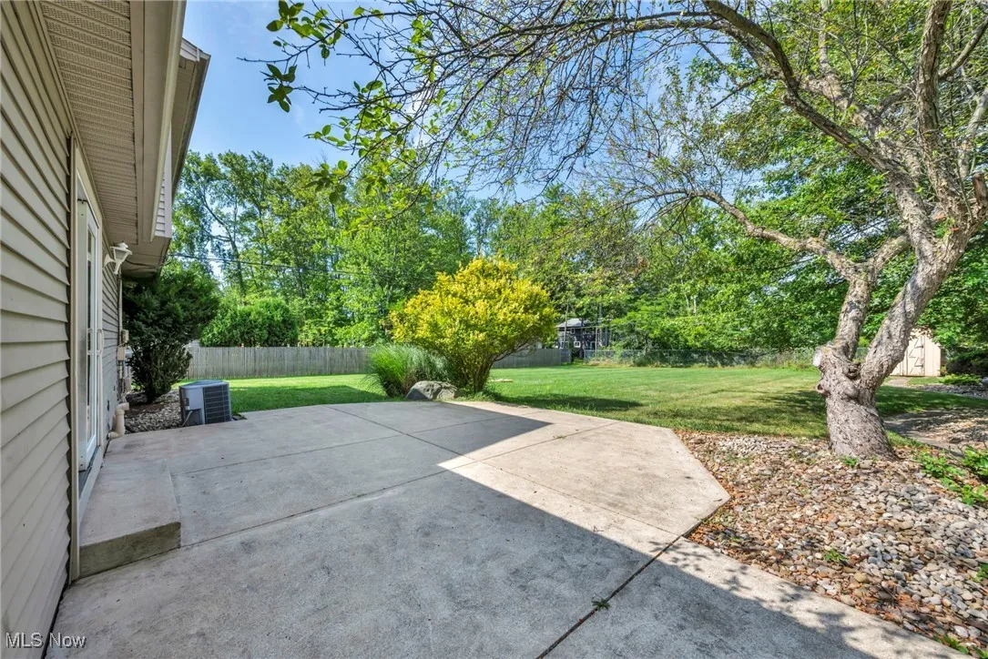 Fenced backyard featuring a patio area and view of wooded area