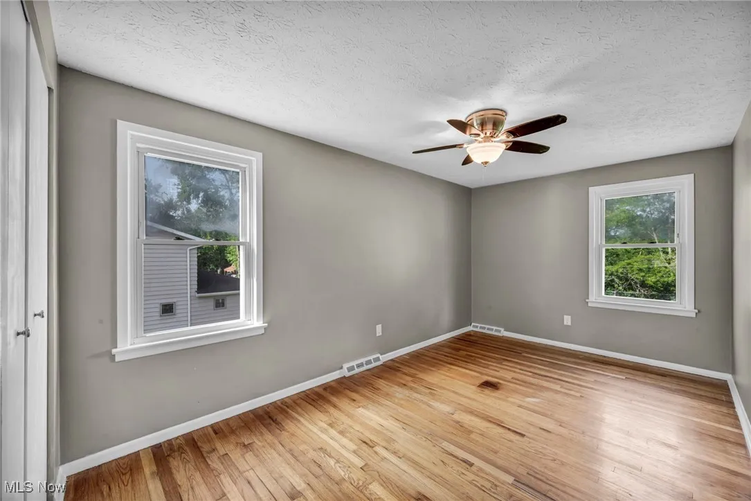 Spare room featuring light wood-style flooring, a textured ceiling, and a ceiling fan