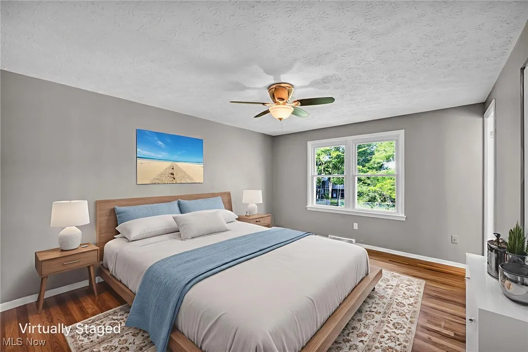 Bedroom featuring ceiling fan, wood finished floors, and a textured ceiling