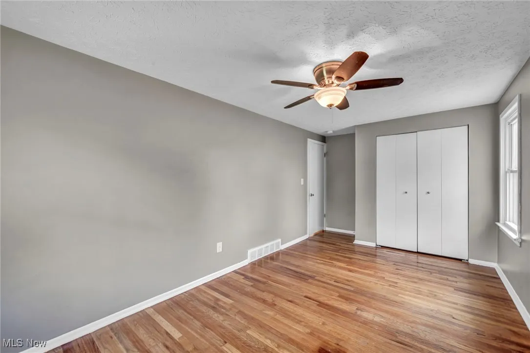 Unfurnished bedroom featuring light wood-type flooring, ceiling fan, a closet, and a textured ceiling
