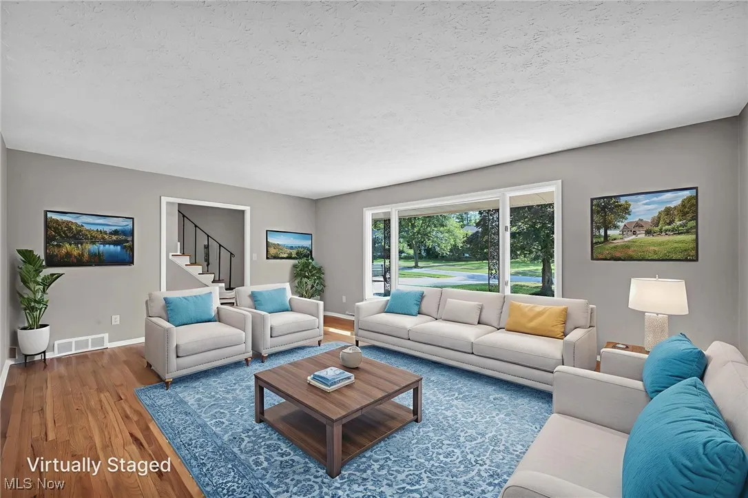 Living area featuring wood finished floors, a textured ceiling, and stairway