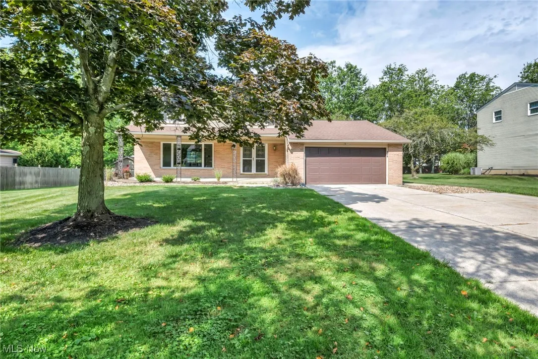 View of front of property with an attached garage, brick siding, driveway, and covered porch