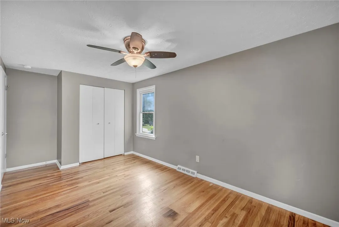 Unfurnished bedroom featuring light wood finished floors, a textured ceiling, a closet, and a ceiling fan