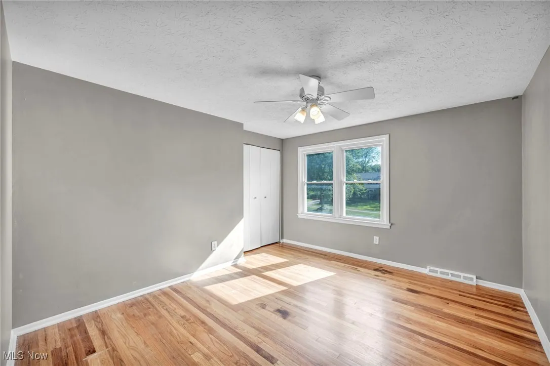 Unfurnished bedroom with light wood-type flooring, a textured ceiling, a closet, and ceiling fan