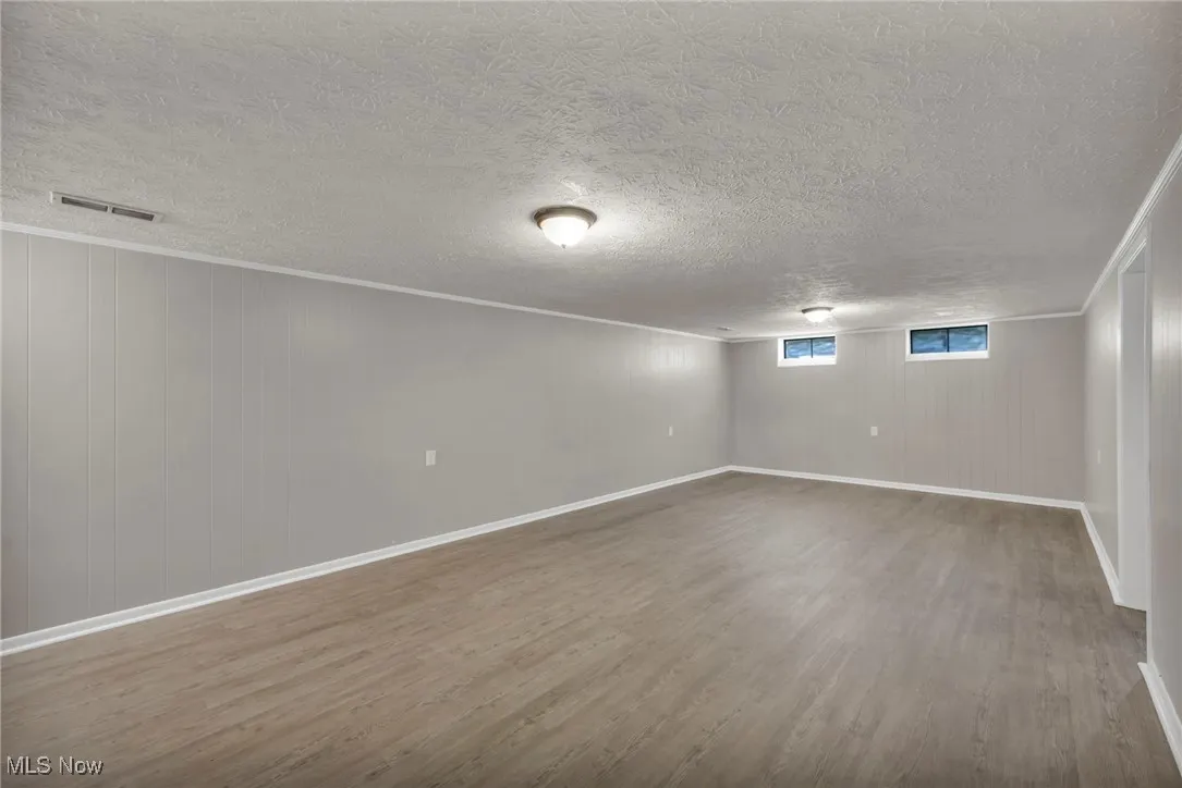 Basement featuring wood finished floors, a textured ceiling, and wood walls