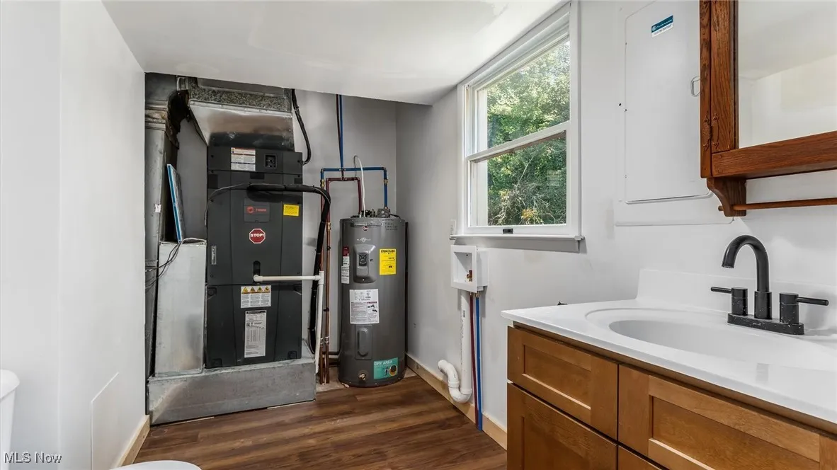 Bathroom featuring water heater, dark wood-style flooring, vanity, and heating unit