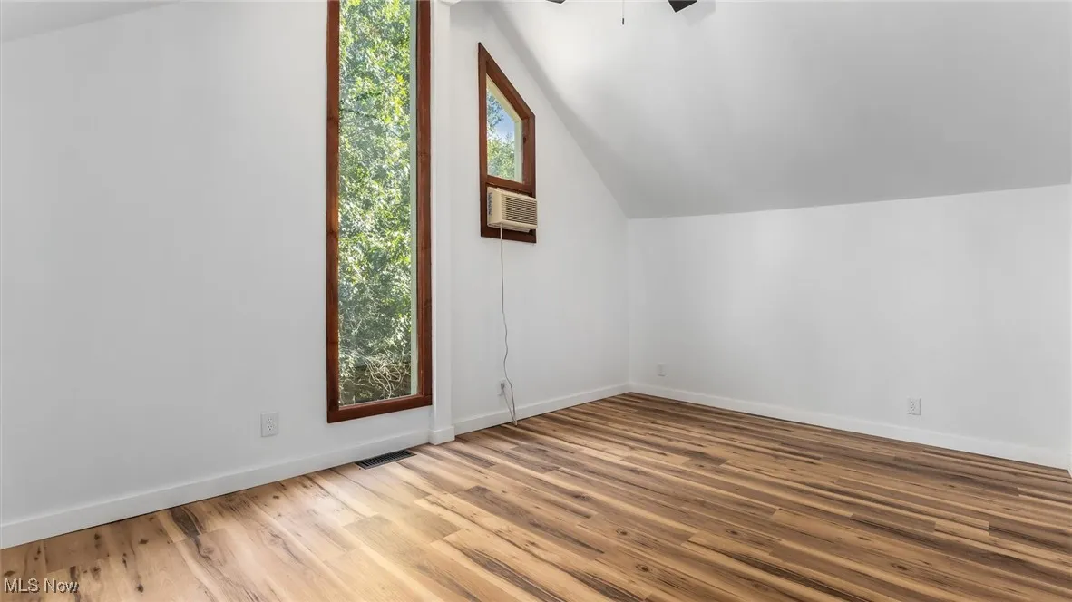 Additional living space featuring vaulted ceiling, wood finished floors, and a ceiling fan