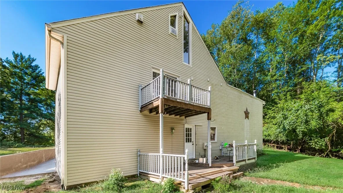 Back of property with a deck and a lawn