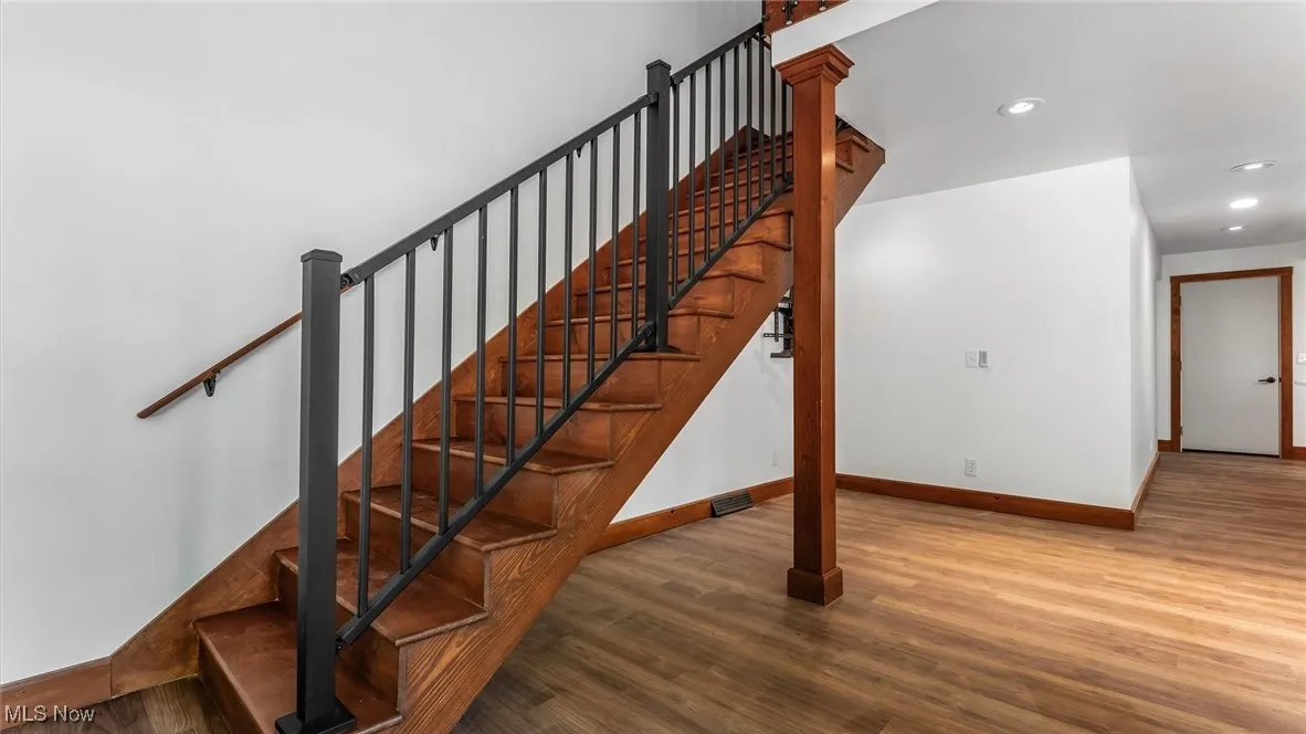 Stairs with wood finished floors and recessed lighting
