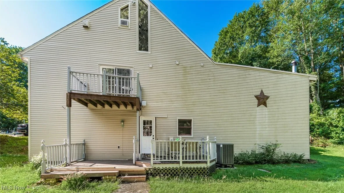 Rear view of property featuring a balcony and a wooden deck