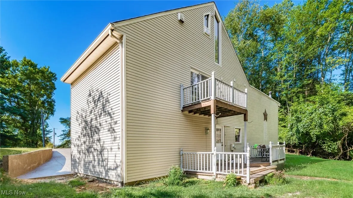 Rear view of house with a wooden deck, a yard, and a balcony