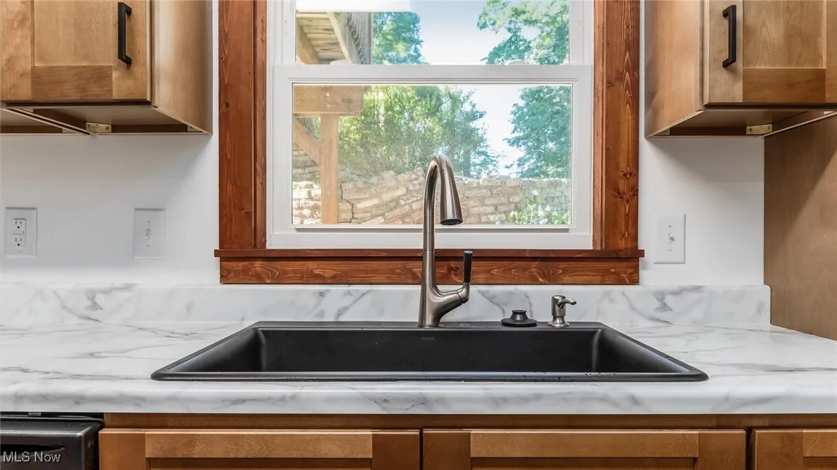 Kitchen featuring brown cabinets and light stone counters