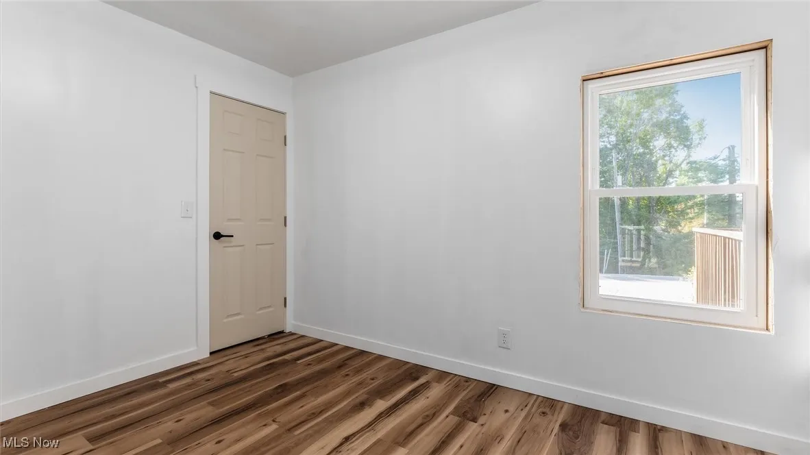 Empty room featuring baseboards and dark wood finished floors