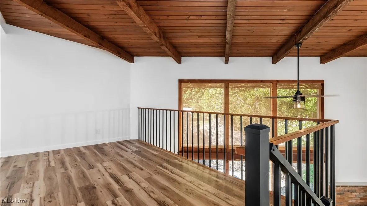 Empty room featuring wood finished floors and a wood ceiling with exposed beams