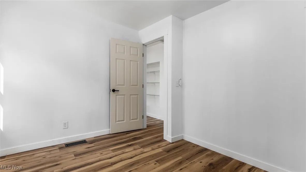 Empty room featuring baseboards and dark wood-style floors