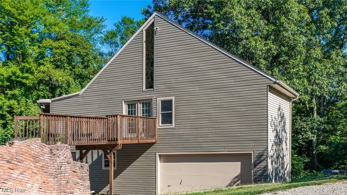 View of side of home with an attached garage and a deck