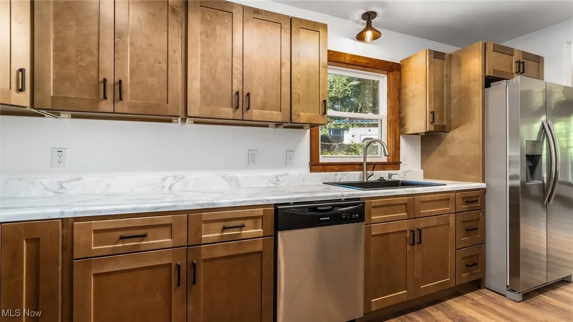 Kitchen featuring appliances with stainless steel finishes, brown cabinets, and light wood-style floors
