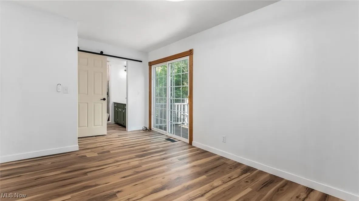 Empty room with a barn door and wood finished floors