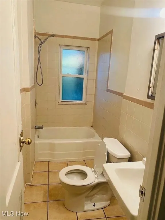 Bathroom featuring tile walls, tub / shower combination, and tile patterned floors