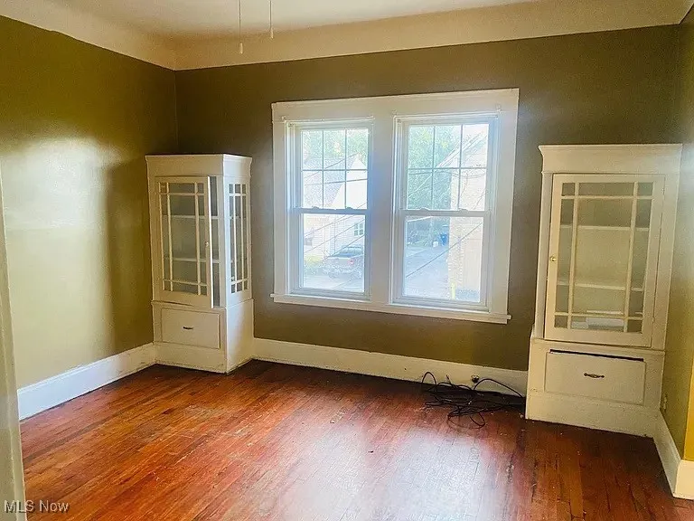 Empty room featuring baseboards and dark wood-style flooring