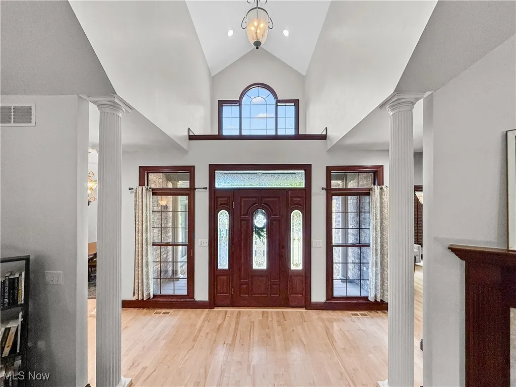 Entryway with decorative columns, light wood-style floors, and high vaulted ceiling