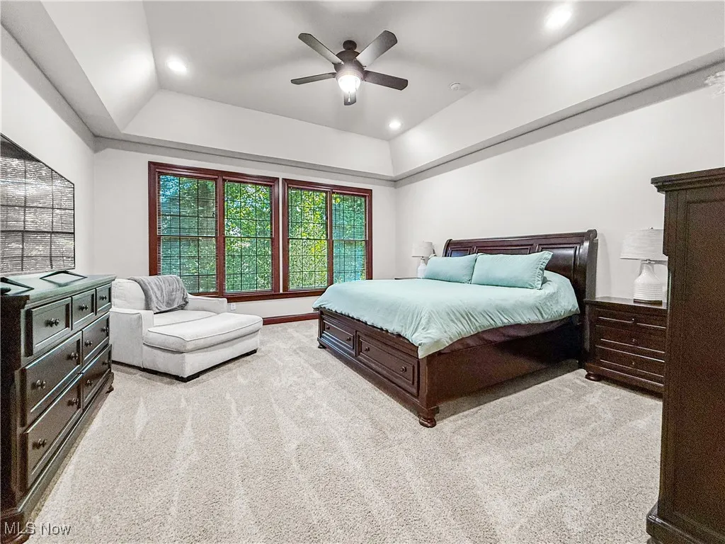 Bedroom with a raised ceiling, light colored carpet, a ceiling fan, and recessed lighting