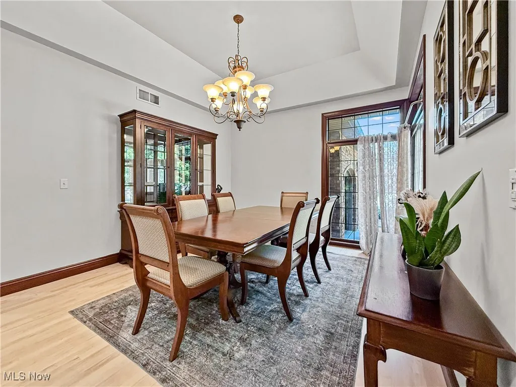 Dining area featuring light wood-style floors, a chandelier, and a raised ceiling