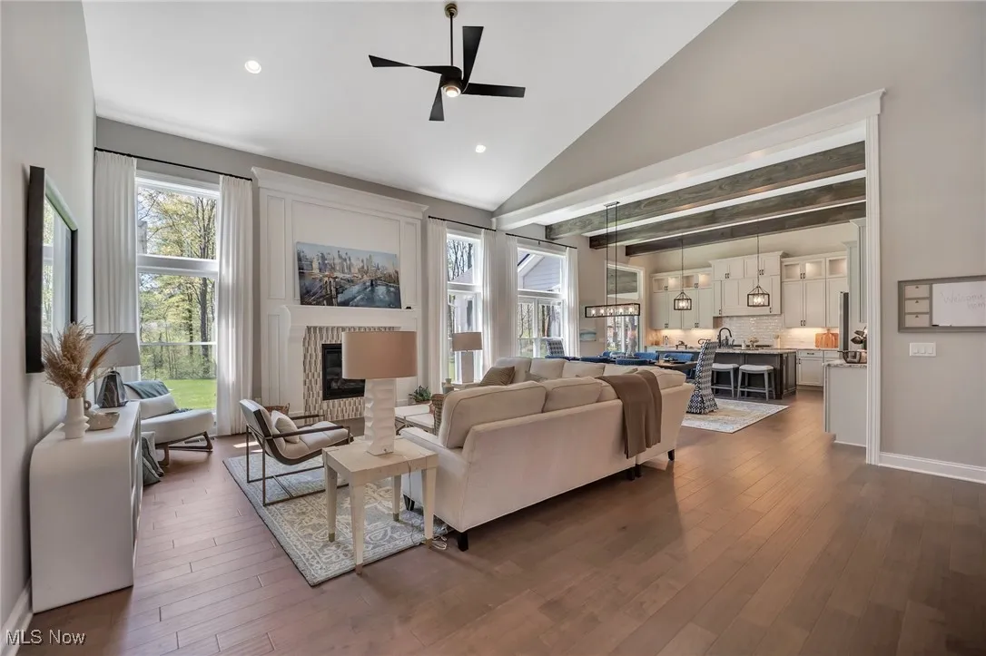 Great room featuring a vaulted ceiling, ceiling fan, healthy amount of natural light, a direct vent fireplace, hardwood flooring, and recessed lighting