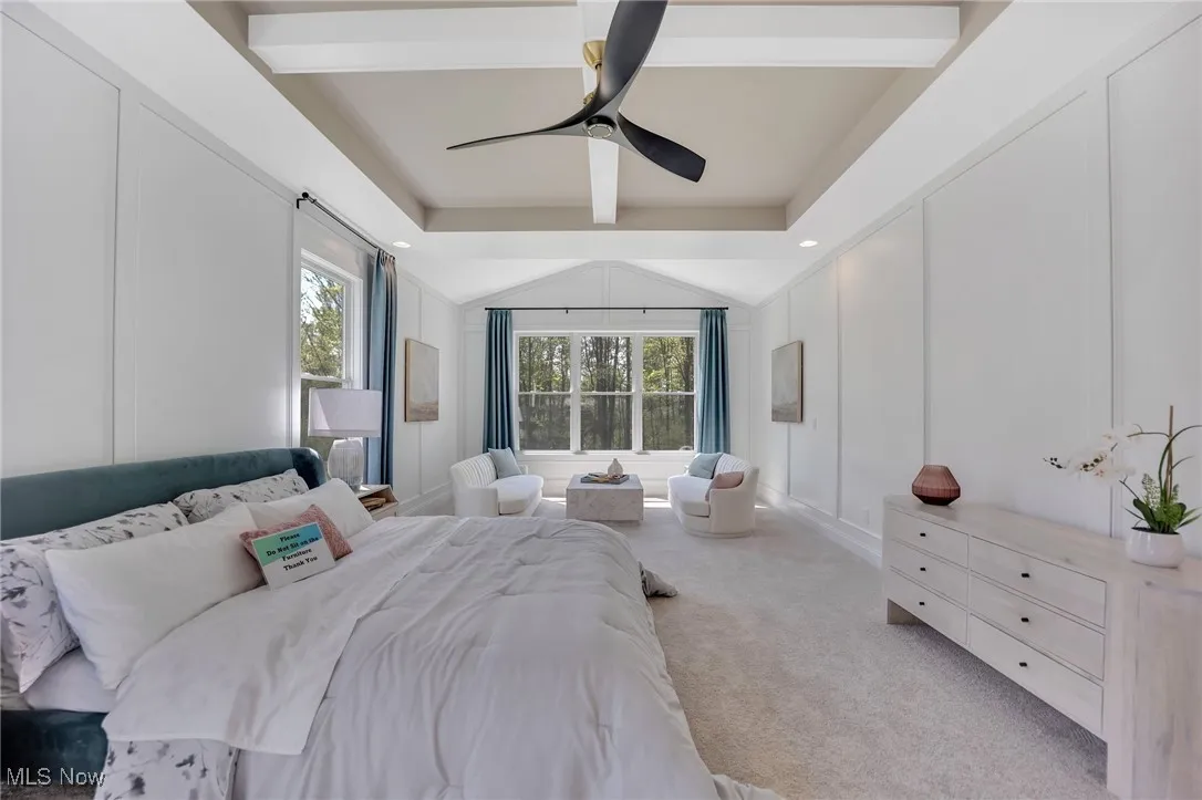 Primary Bedroom with multiple windows, floor to ceiling wainscotting, carpet flooring, ceiling fan, sitting room and coffered ceiling