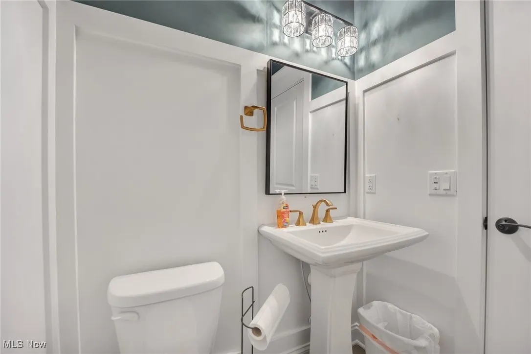 Half bathroom featuring wainscotting, pedestal sink and elongated commode