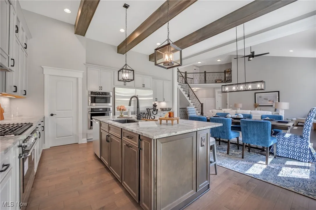 Kitchen featuring pendant light fixtures, beam ceiling, leather finished granite countertops, stainless steel appliances, and a walk in pantry