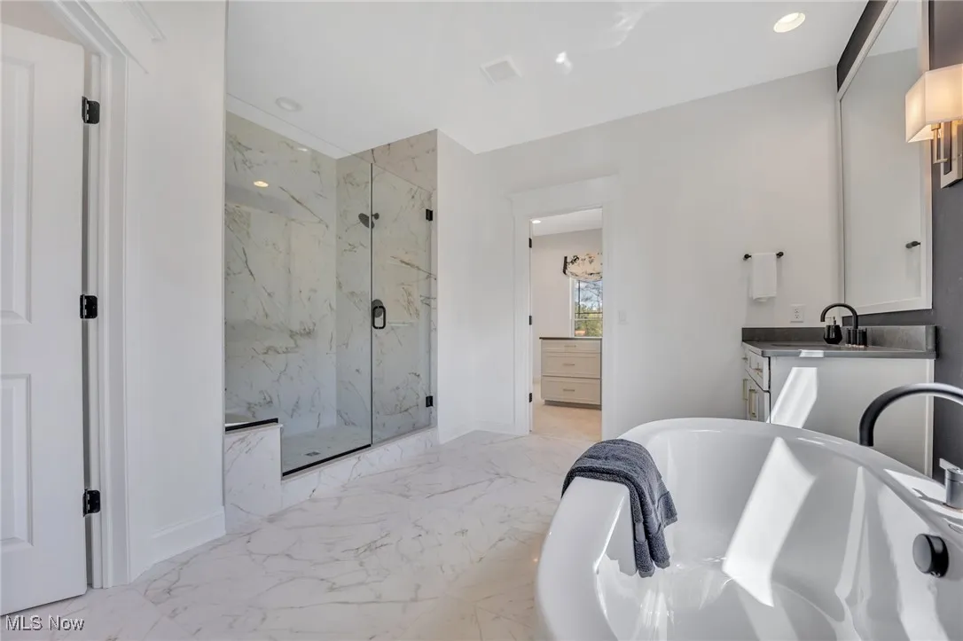 Primary bathroom large tile shower, a freestanding bath, light marble finish floors, quartz countertops and recessed lighting