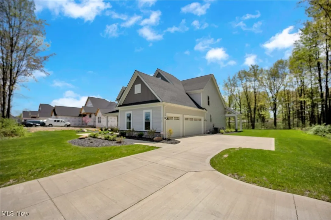 View of side of home featuring a lawn, driveway, and an 3 car attached garage