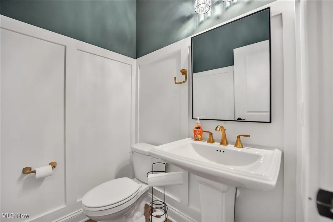 Half bathroom featuring wainscotting, pedestal sink and elongated commode