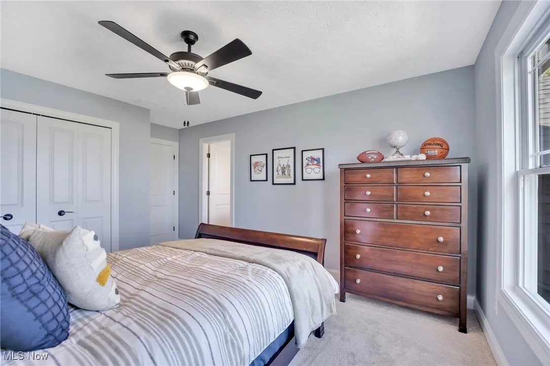 Bedroom featuring carpet floors, a ceiling fan, a closet, multiple windows, and a textured ceiling