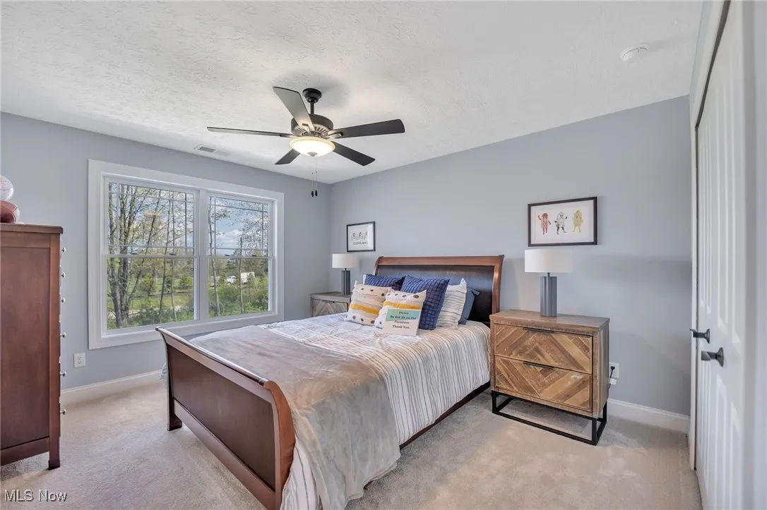 Bedroom featuring light colored carpet, a textured ceiling, and ceiling fan