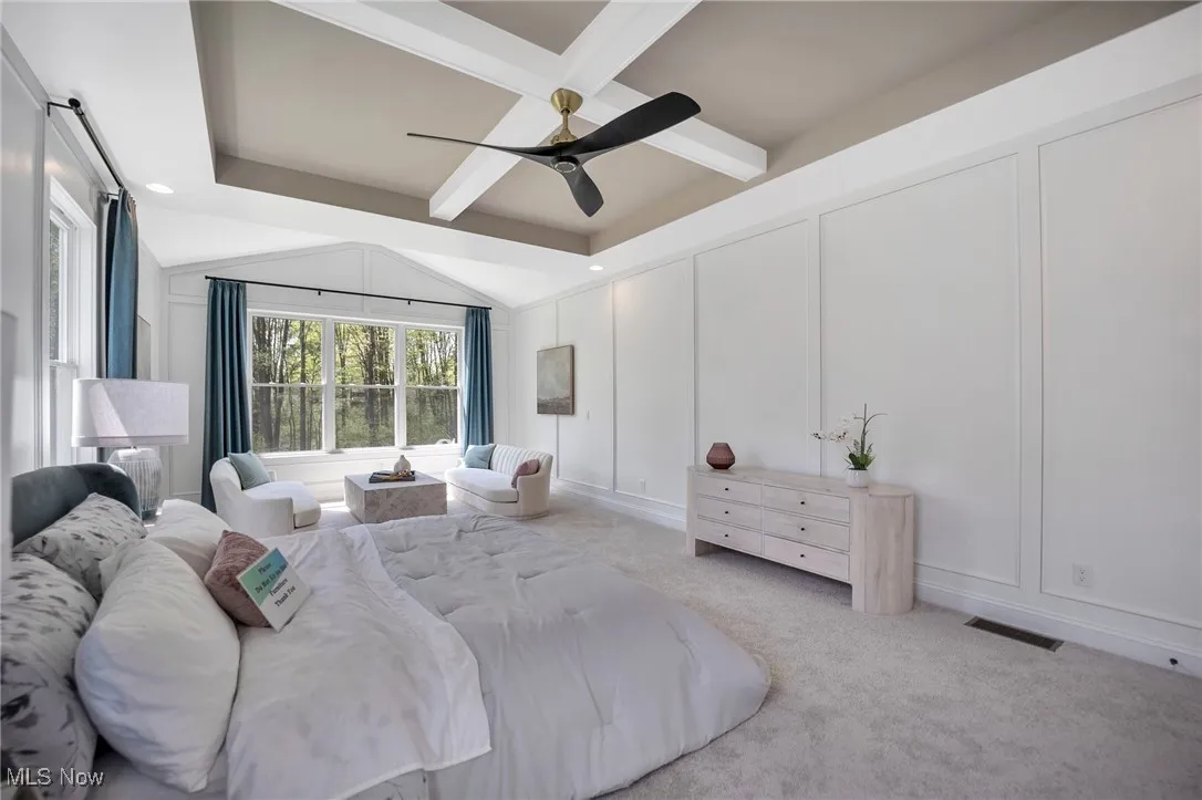 Primary Bedroom with multiple windows, floor to ceiling wainscotting, carpet flooring, ceiling fan, sitting room and coffered ceiling