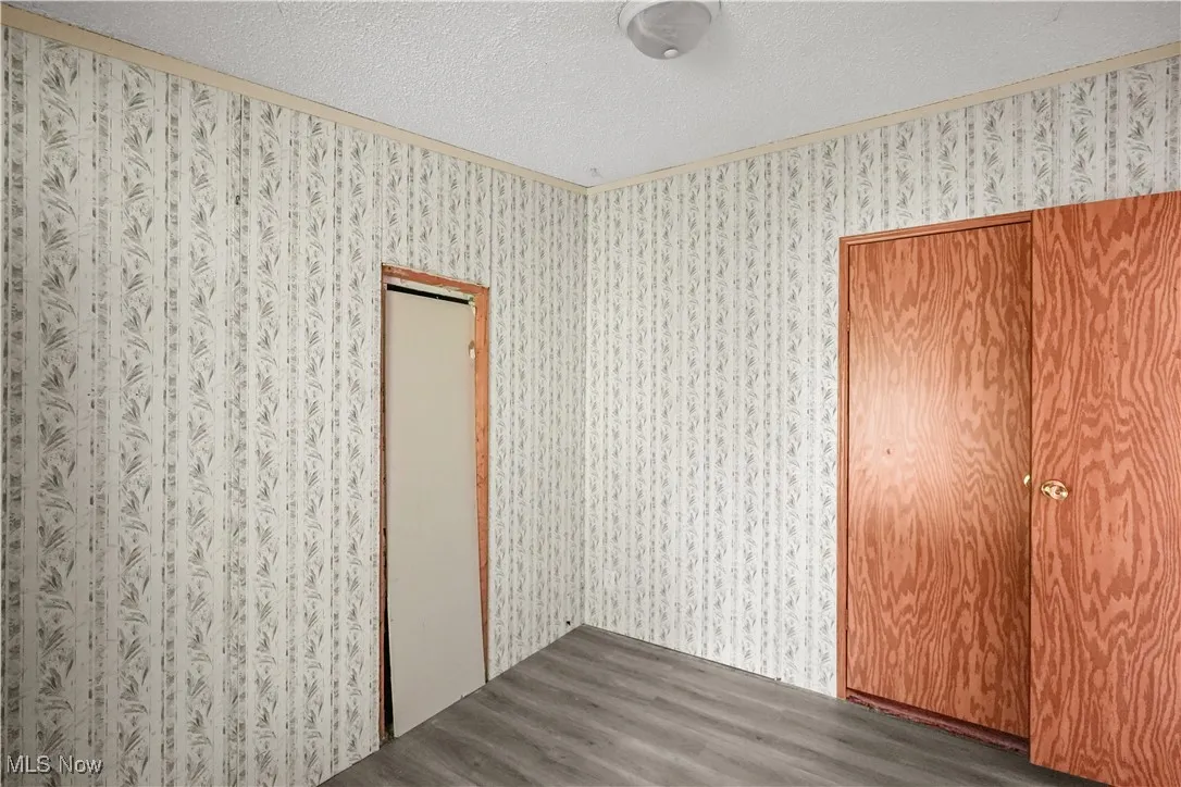Unfurnished room featuring dark wood finished floors, a textured ceiling, and ornamental molding