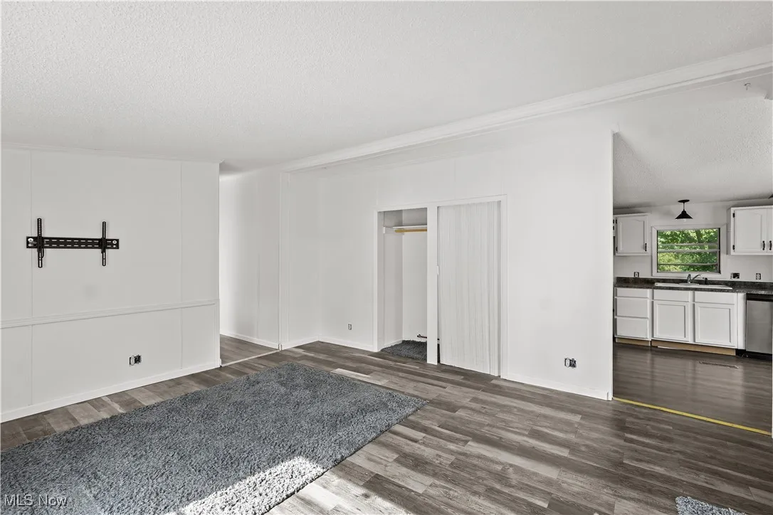 Unfurnished living room featuring a textured ceiling and dark wood-type flooring