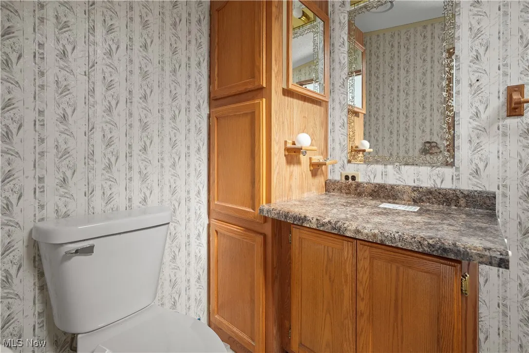 Bathroom featuring wallpapered walls and vanity