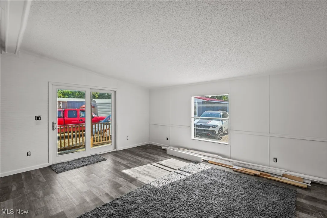 Spare room featuring lofted ceiling, a textured ceiling, dark wood-style flooring, and a decorative wall
