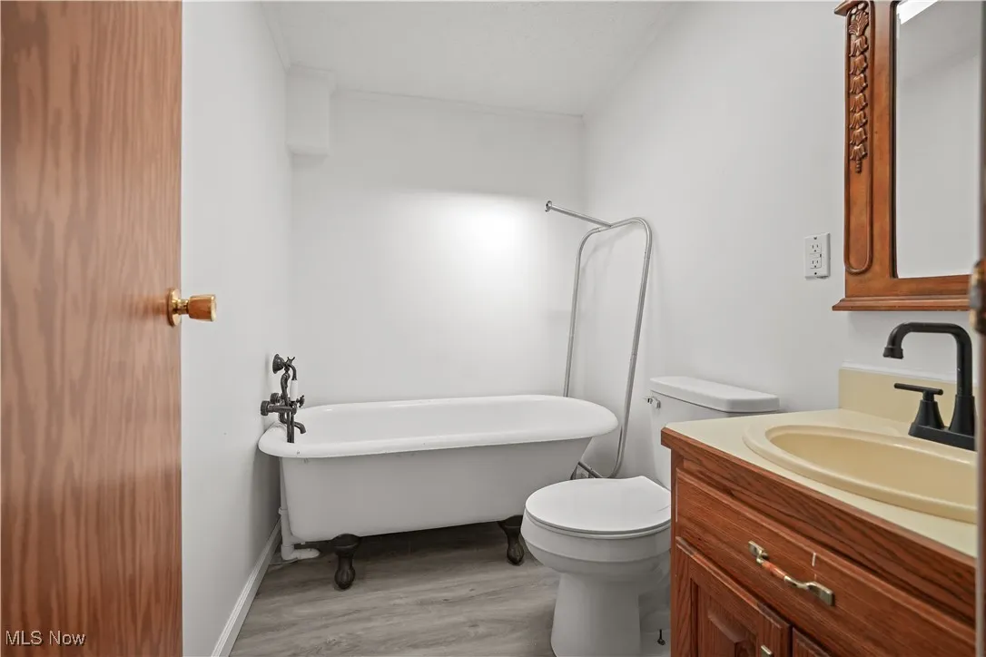 Full bathroom featuring a soaking tub, vanity, light wood-style flooring, and a textured ceiling