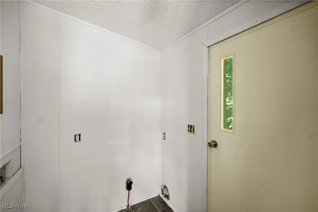 Washroom with a textured ceiling and dark tile patterned flooring