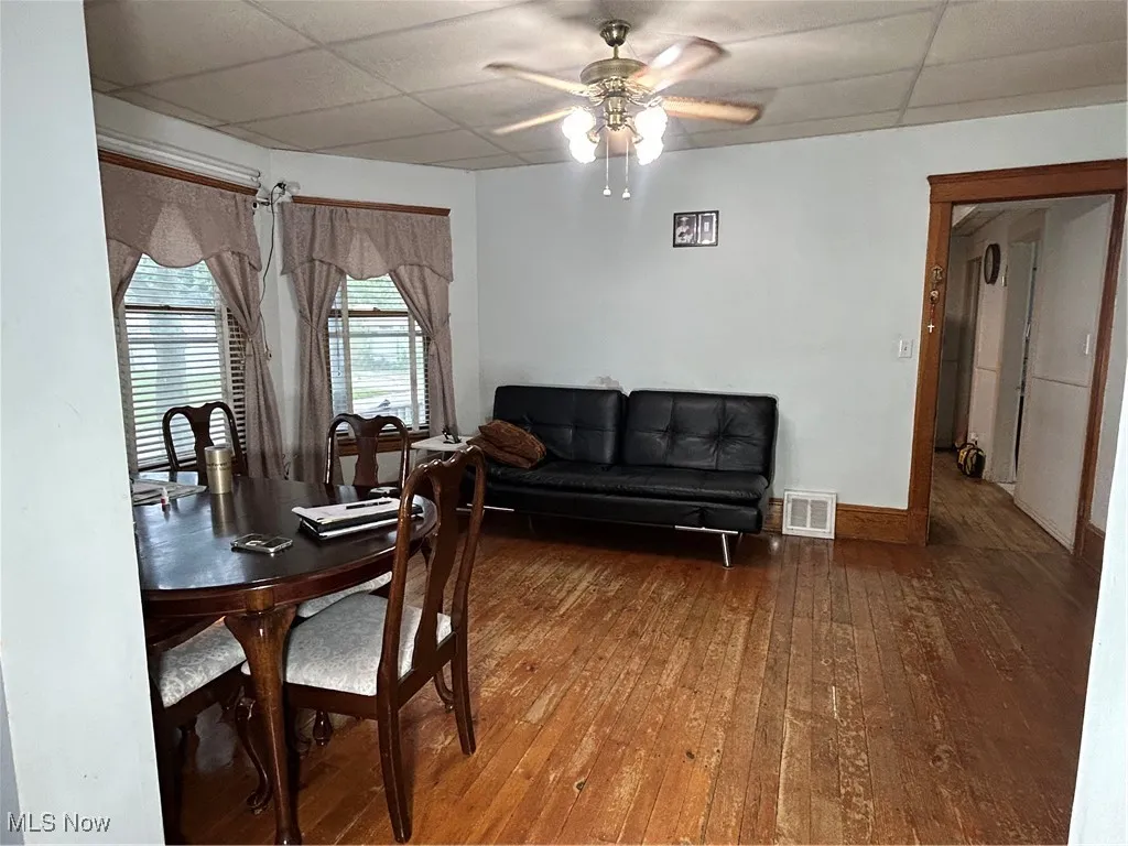 Dining area featuring a drop ceiling, dark wood-style floors, and a ceiling fan