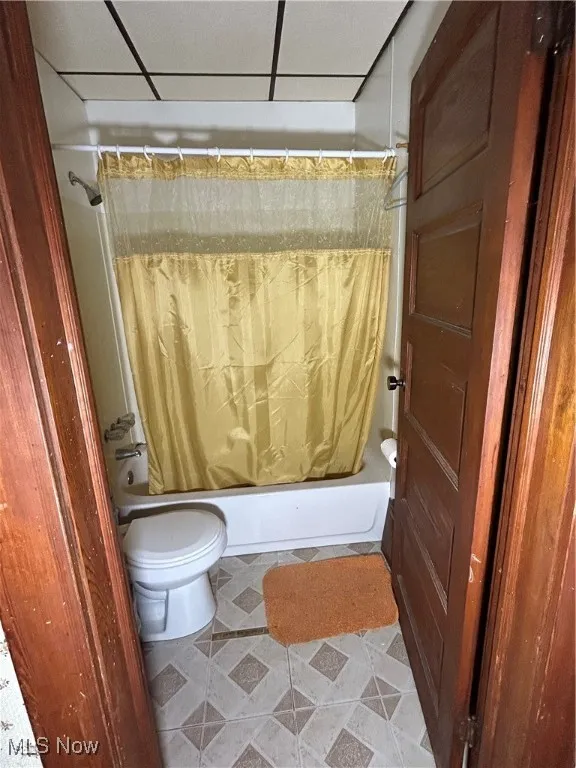 Full bathroom featuring shower / bath combo with shower curtain and light tile patterned flooring