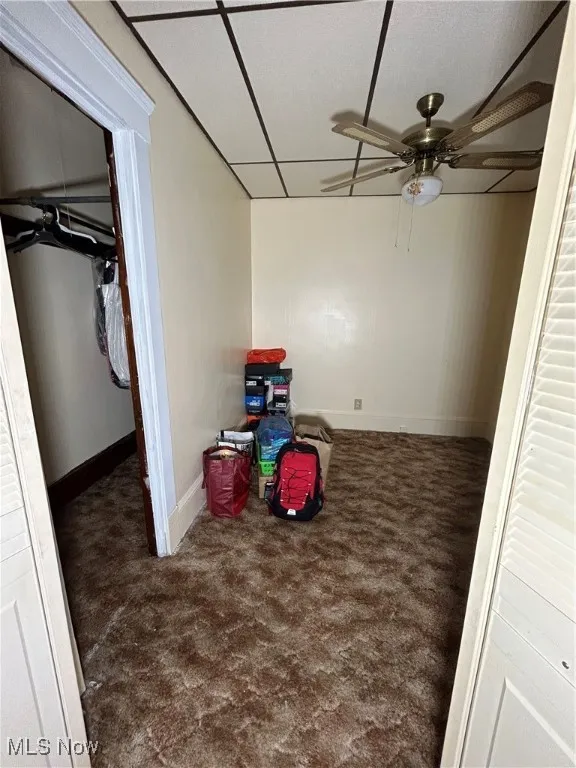 Recreation room with ceiling fan and dark carpet