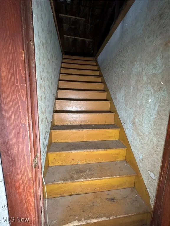 Staircase featuring wallpapered walls