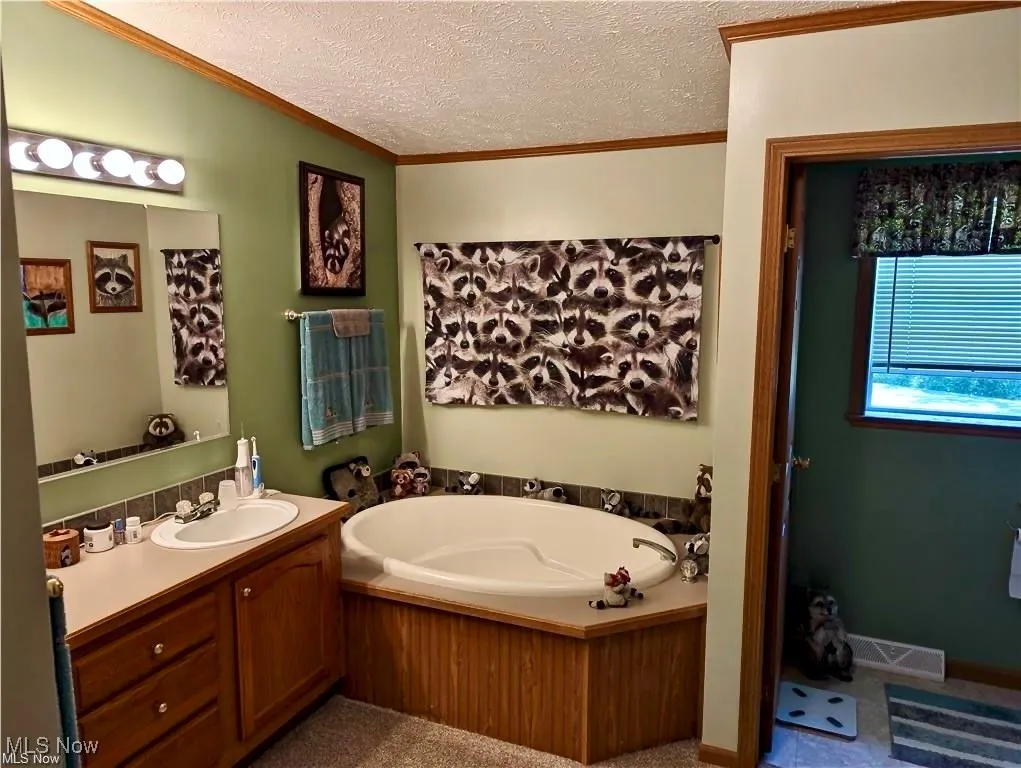 Bathroom with a textured ceiling, a soak tub, shower, vanity, and crown molding